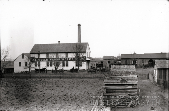 A view of the J.I. Nissen Wagon Works with workers and wagons lined up outside the building.