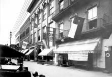 A building with a flags hanging outside, one of which reads "North Carolina Equal Suffrage Association." 